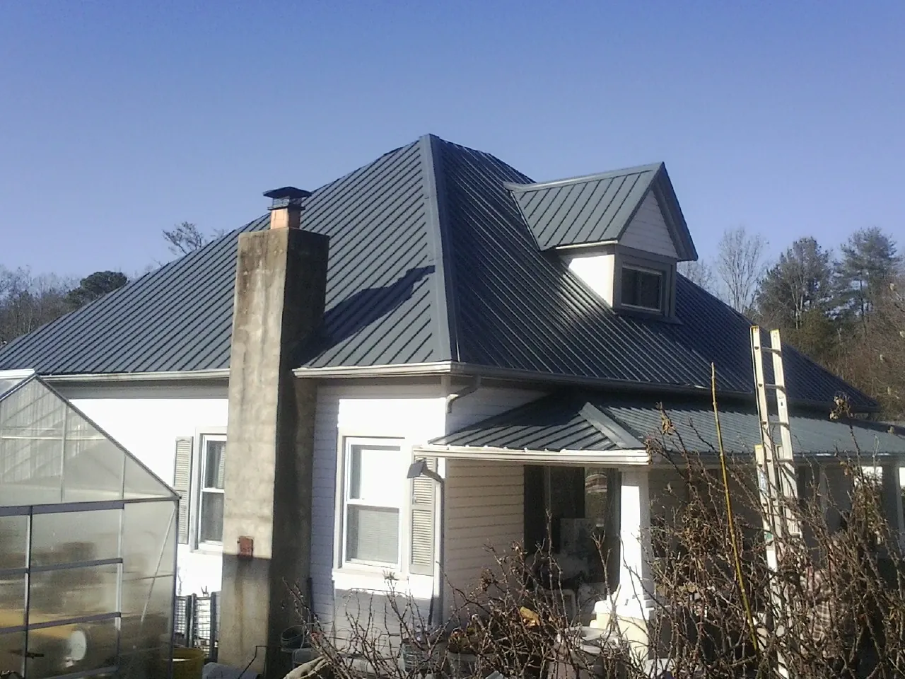 Dark blue standing seam metal roof on a white farmhouse with dormer — Slate & Tile Roof Repair by Roofing Brothers in Tiplersville
