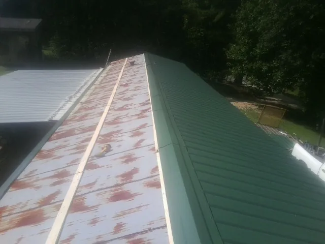Old rusted panels beside newly installed green metal roofing — Wind Damage Roof Repair by Roofing Brothers in Tiplersville