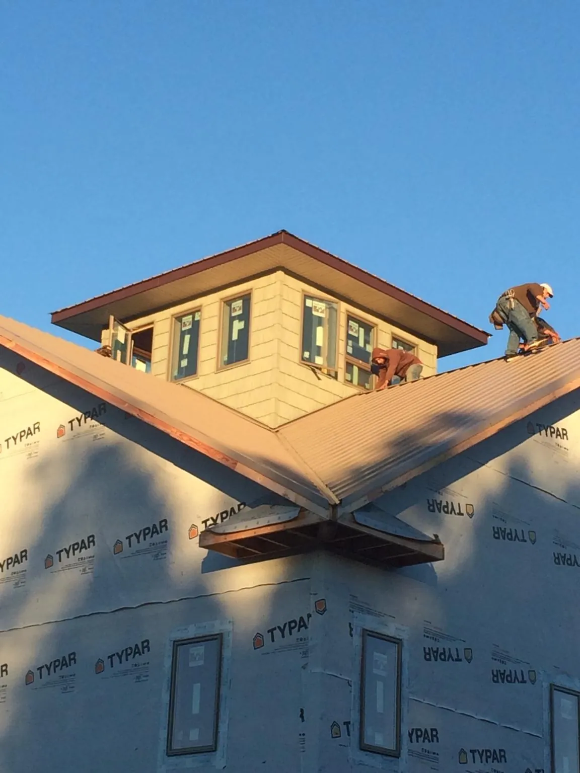 Roofers working around a rooftop cupola on a new metal roof at sunset — Roof Waterproofing in Tiplersville by Roofing Brothers
